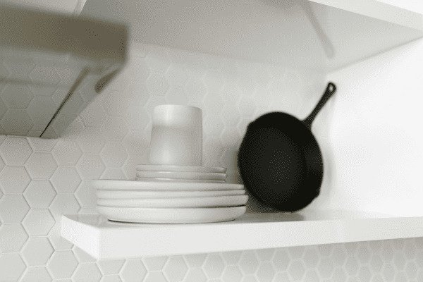 Prateleira-branca-de-cozinha-com-pratoscopo-branco-e-frigideira-preta-ao-lado-Descubra-o-Poder-do-Minimalismo-O-Estilo-de-Vida-Simples.jpg