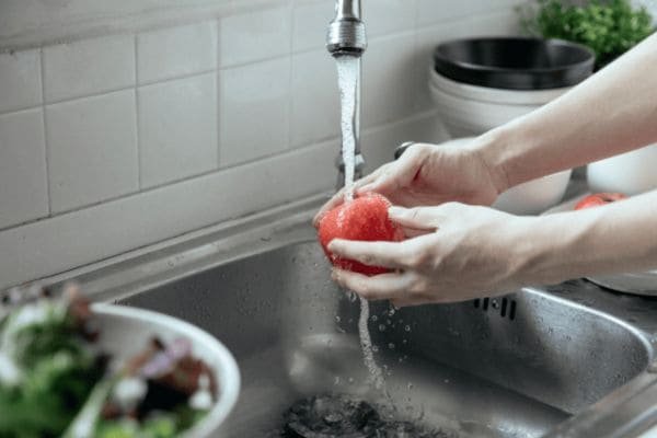 maos-lavando-tomate-na-pia-Veja-Como-Facilitar-Sua-Rotina-com-uma-Alimentacao-Saudavel-e-Equilibrada