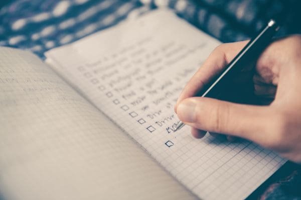 Checklist da organização-mão escrevendo lista com caneta em caderno