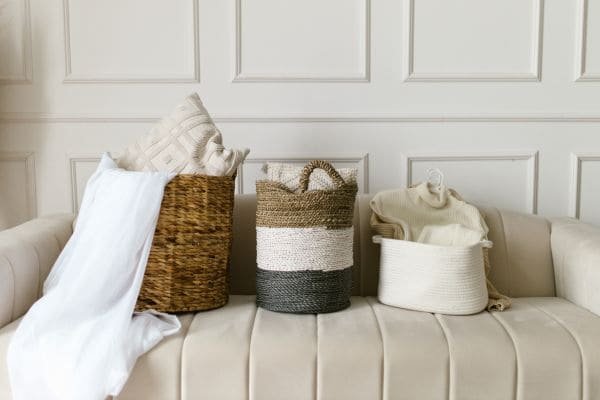 Três cestos de cores e tamanhos diferentes com objetos em cima do sofá-coisas para eliminar